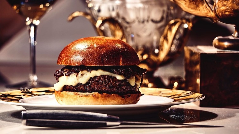 Burger with melted white cheese on a white plate