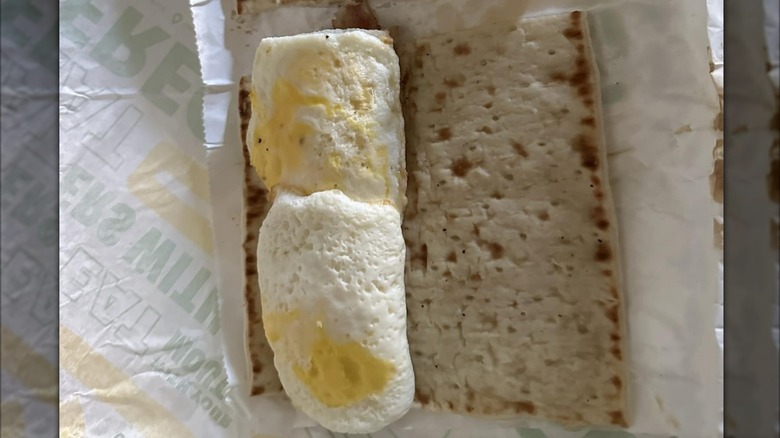 Egg patties sit on a flatbread as part of a Subway breakfast sandwich