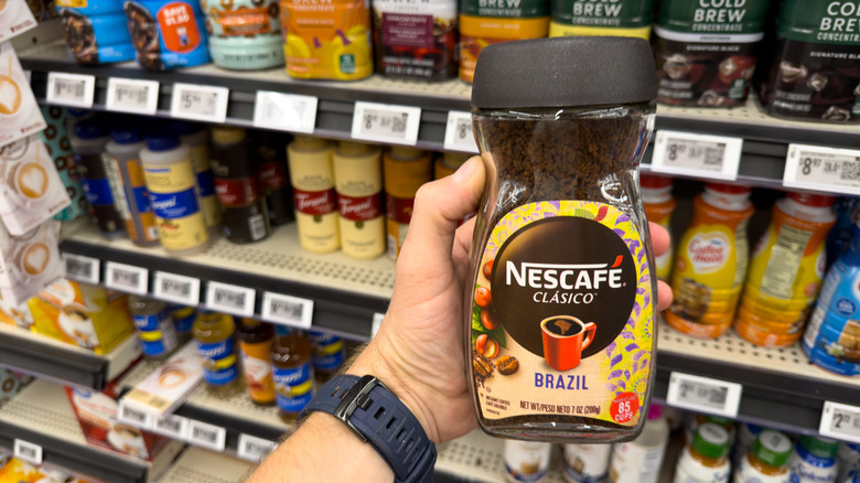 Person holds Nescafe coffee in hand.