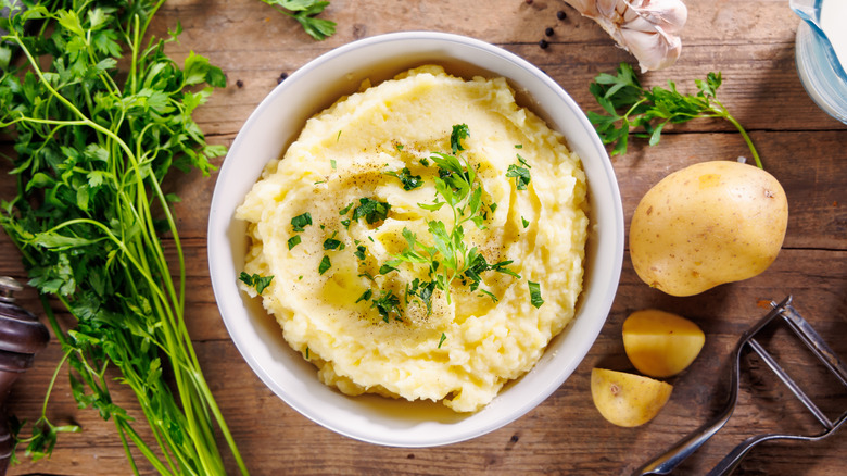 A bowl of mashed potatoes on a wooden table.