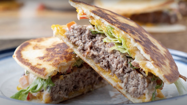 A halved quesadilla burger featuring a ground beef patty and melted cheese stacked on a plate