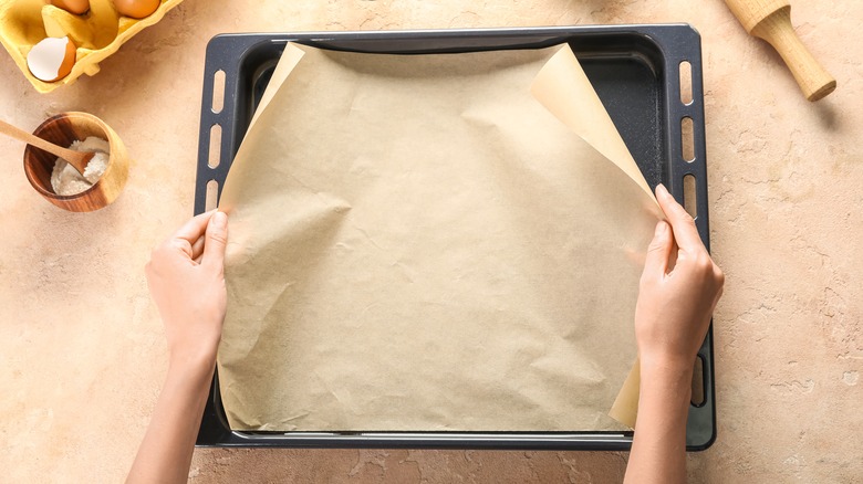 Woman's hands lining baking tray with parchment paper
