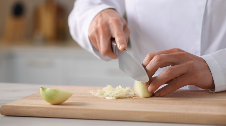 Chef chopping onions on board