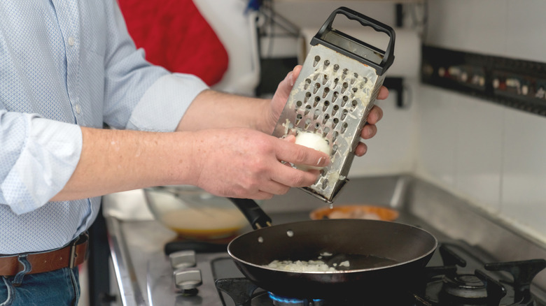 Man grating onion into pan