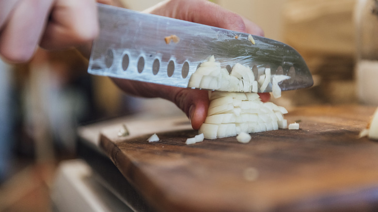 cutting a white onion on a cutting board