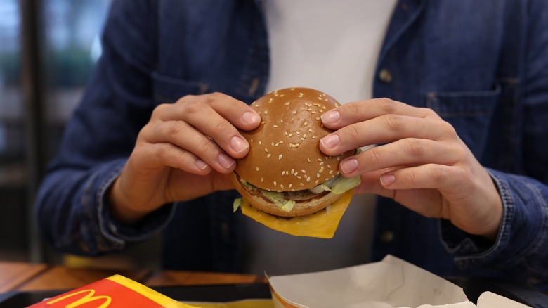 A person holding a Big Mac in a McDonald's