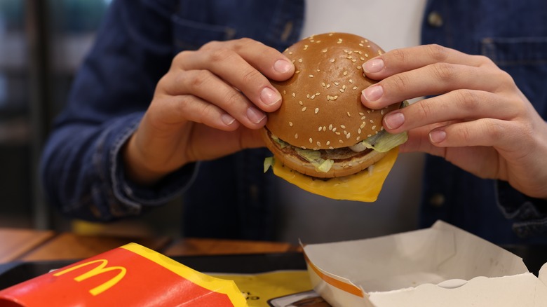 A person holding a Big Mac in a McDonald's