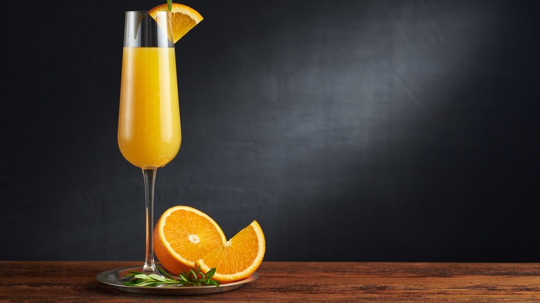 classic mimosa in a flute next to cut oranges