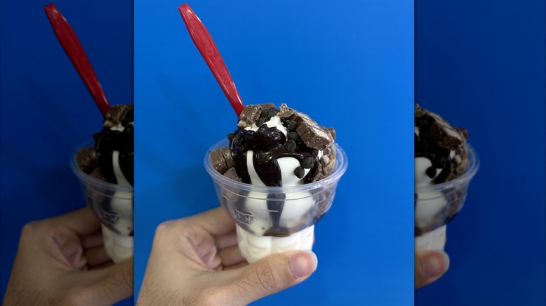 Person holding Dairy Queen sundae in hand.