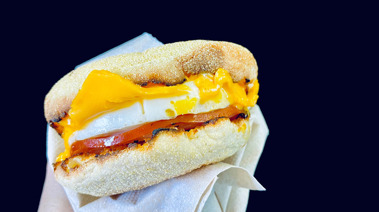 A classic Egg McMuffin with Canadian bacon, egg, and cheese held in a hand.