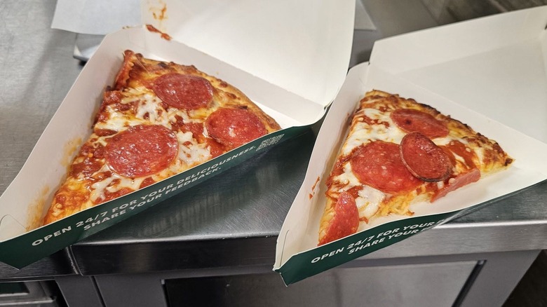 Two slices of 7-Eleven pizza sit in their boxes.