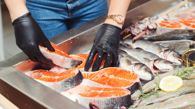 Hands selecting from fish on ice