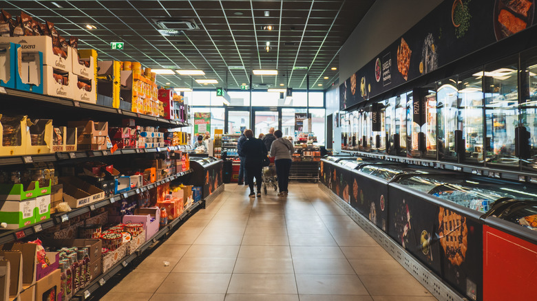 The view of an Aldi aisle midday, with two individuals shopping.