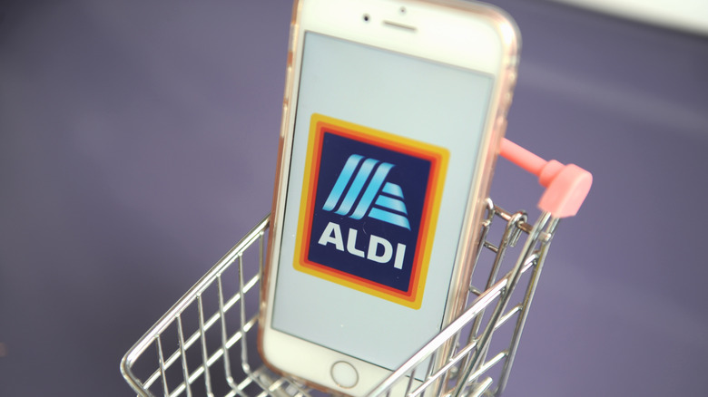 Smartphone in the mini shopping cart with logo of Aldi retail company.