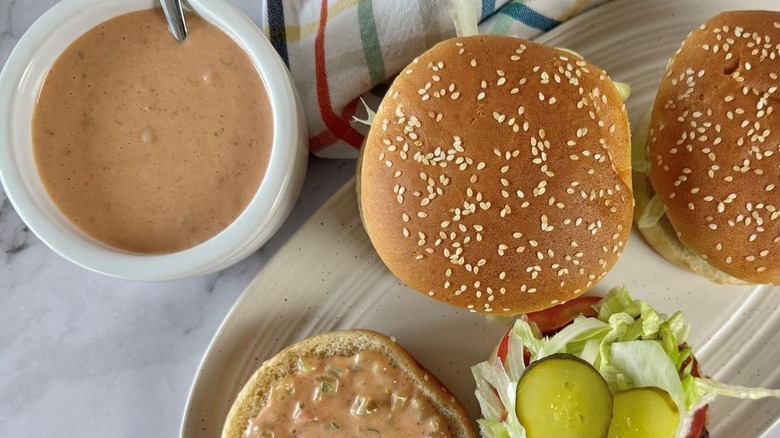 Burger sauce in bowl next to burgers on plate
