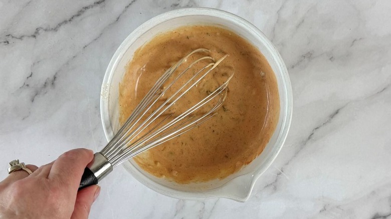 Hand whisking burger sauce in bowl