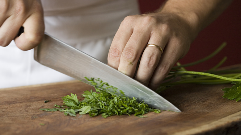 hands chopping parsley with knife