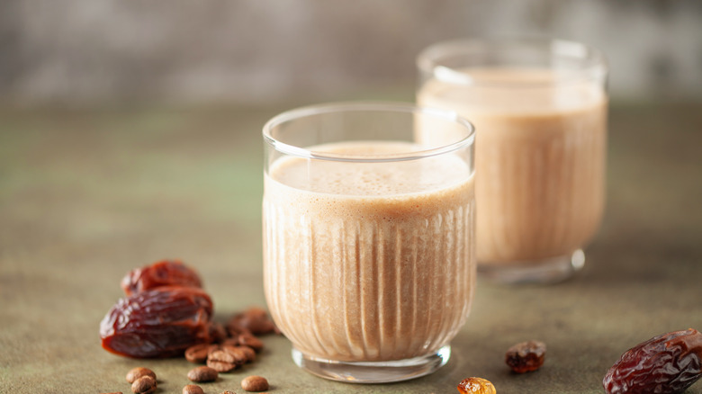 prepared date shakes in small glasses next to some whole dates