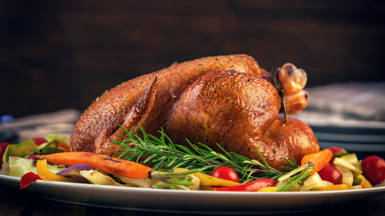 roast chicken surrounded by cooked veggies