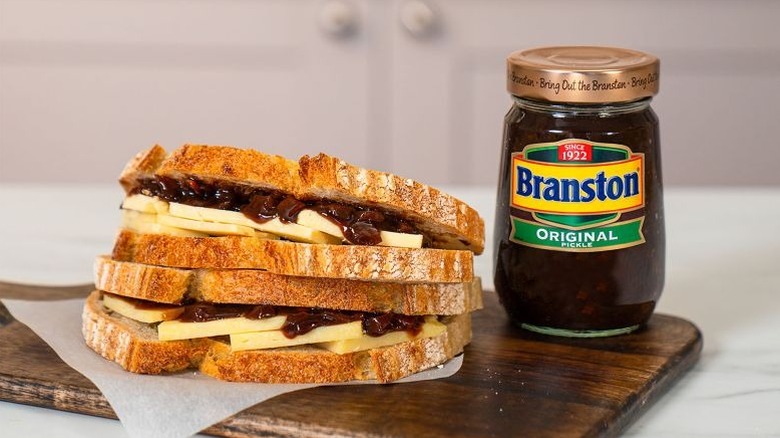 Two cheese and Branston Pickle sandwiches on top of each other with a jar of the chunky brown condiment