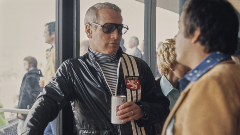 Paul Newman relaxes with a canned drink at a racing event.