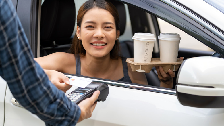 Woman smiling while holding to-go coffees in drive-thru