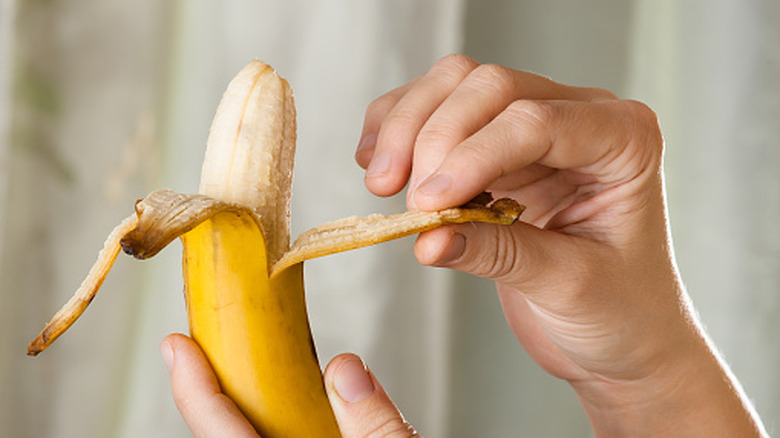 A hand peels a banana