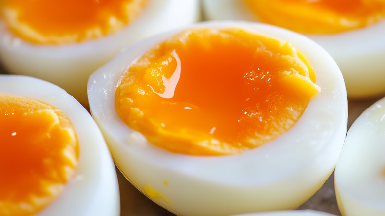 Soft-boiled eggs sit, cut open, to reveal their jammy yolks