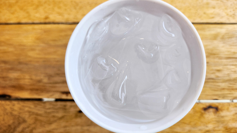 A bowl of ice water sits on a wooden surface