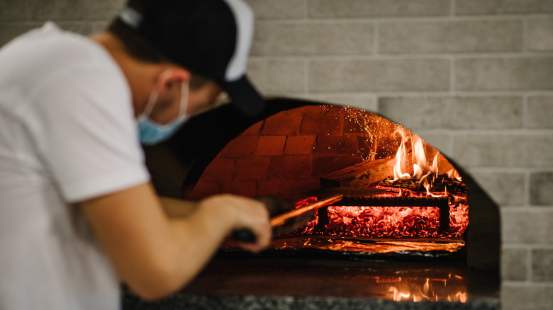 Man stokes a wood-fired oven