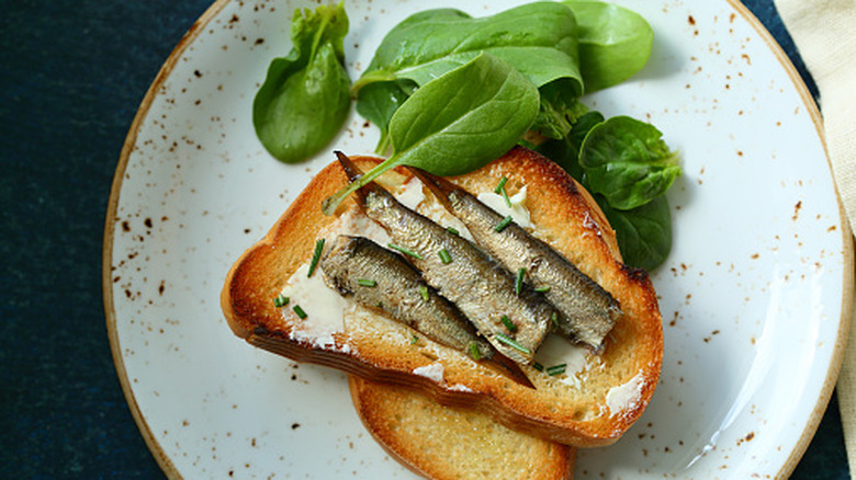 Toast topped with sardines, mayo, and chives with a side of spinach.