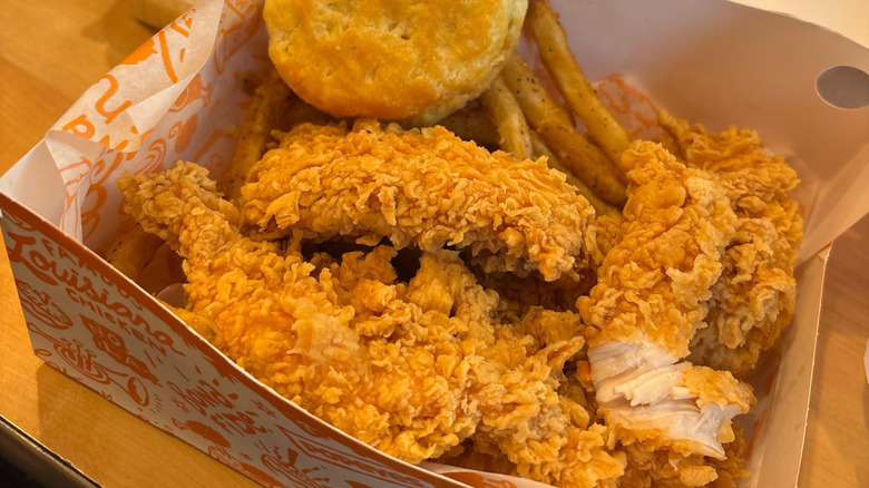 A box of chicken tenders and a biscuit and fries from Popeyes