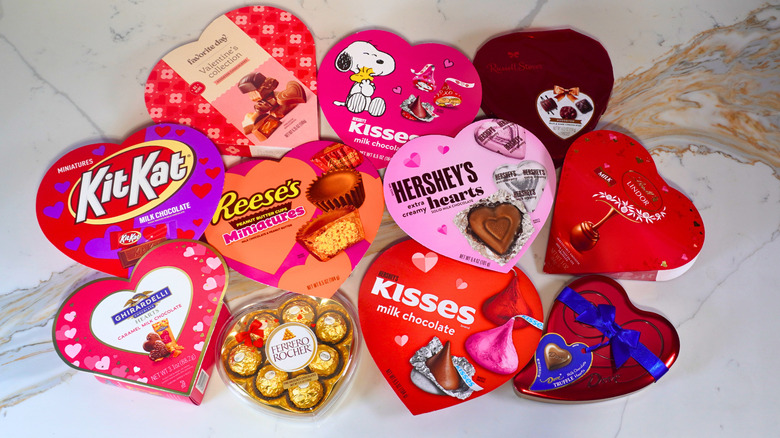 Eleven closed heart-shaped boxes of chocolate arranged on a marble counter