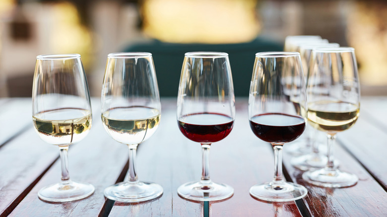 A lineup of red and white wine glasses on a wooden table outside