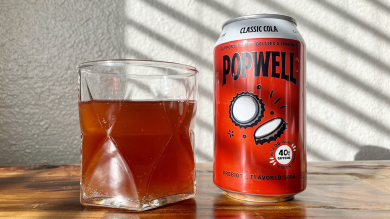 Can and glass of Popwell Classic Cola on a wooden table