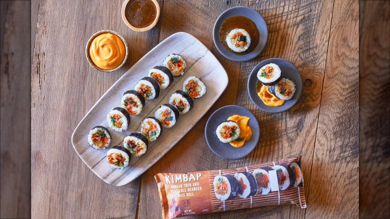 A package of Trader Joe's Kimbap sits next to a sushi-style plate and small round dishes containing kimbap pieces