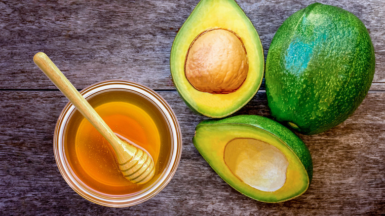 Overhead view of sliced avocado and bowl of honey