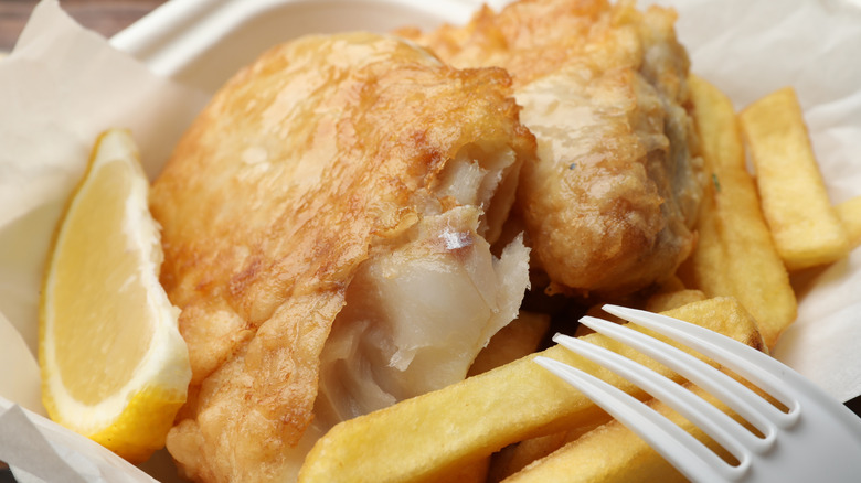 Fish and chips with a lemon wedge in a takeout container