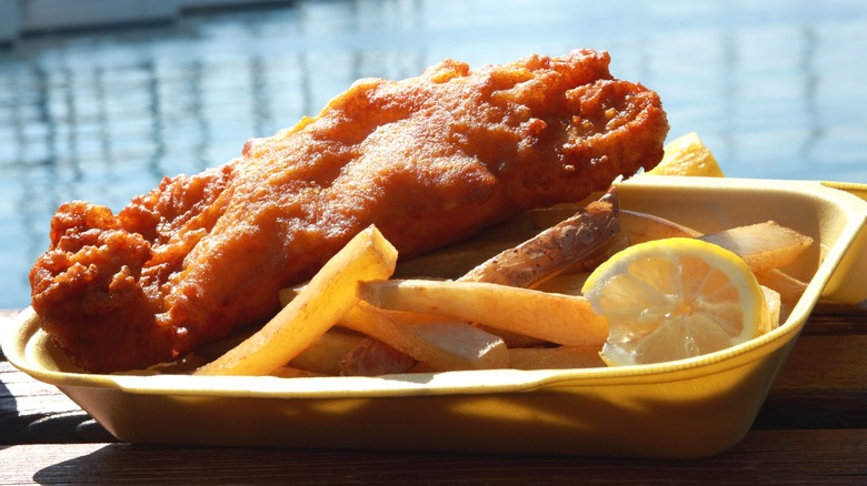Fish and chips in a takeout container by the waterside