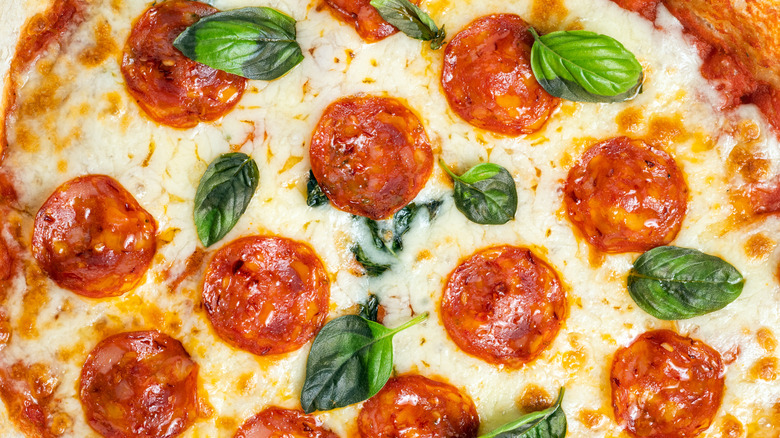 Pepperoni pizza with basil leaves.