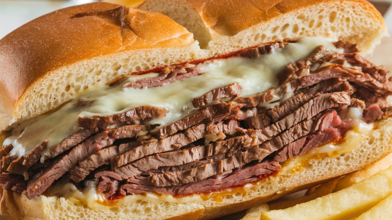 A Philly cheesesteak close up next to fries