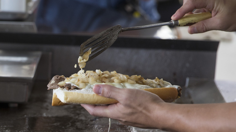 A cook assembles a Philly cheesesteak