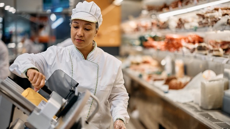 A deli worker slicing cheese