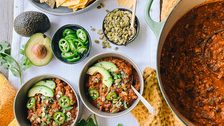 Pumpkin and turkey chili served on table with garnishes
