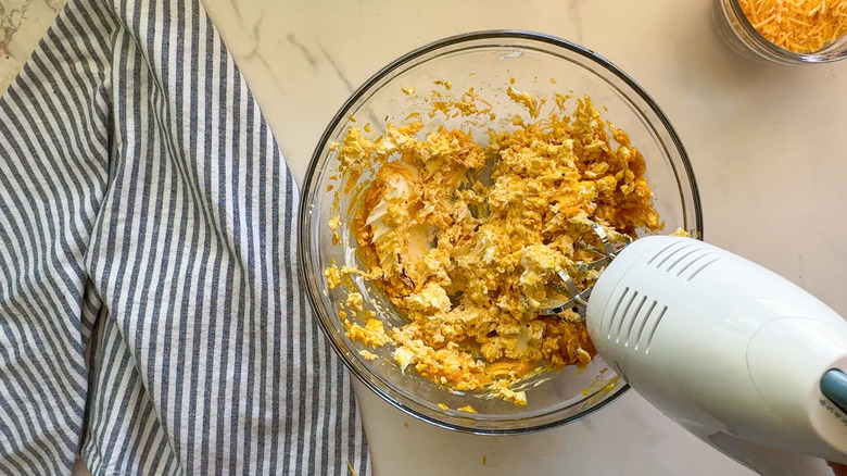 Electric hand mixer beating pumpkin cream cheese mixture in bowl