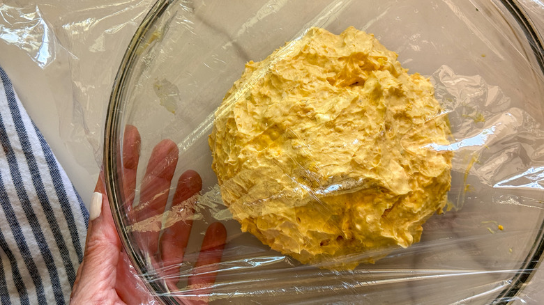 bowl with cheese ball covered in plastic wrap