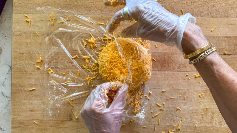 hands wrapping cheese ball in plastic wrap