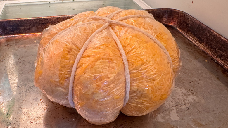 cheese ball wrapped in twine on pan in fridge