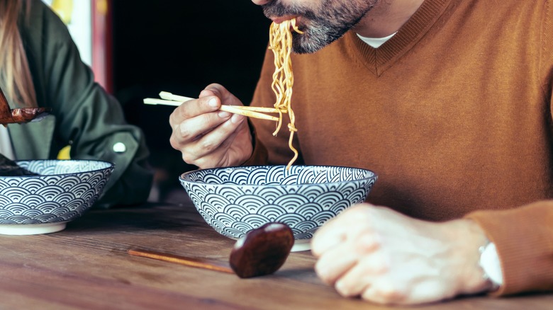 Coupe eating ramen in restaurant