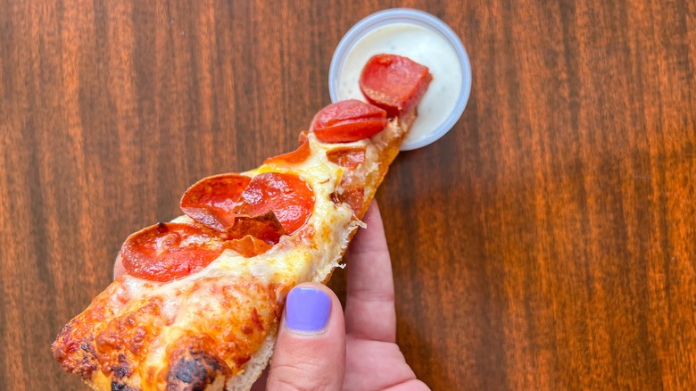 Slice of pizza dipped into ranch dressing